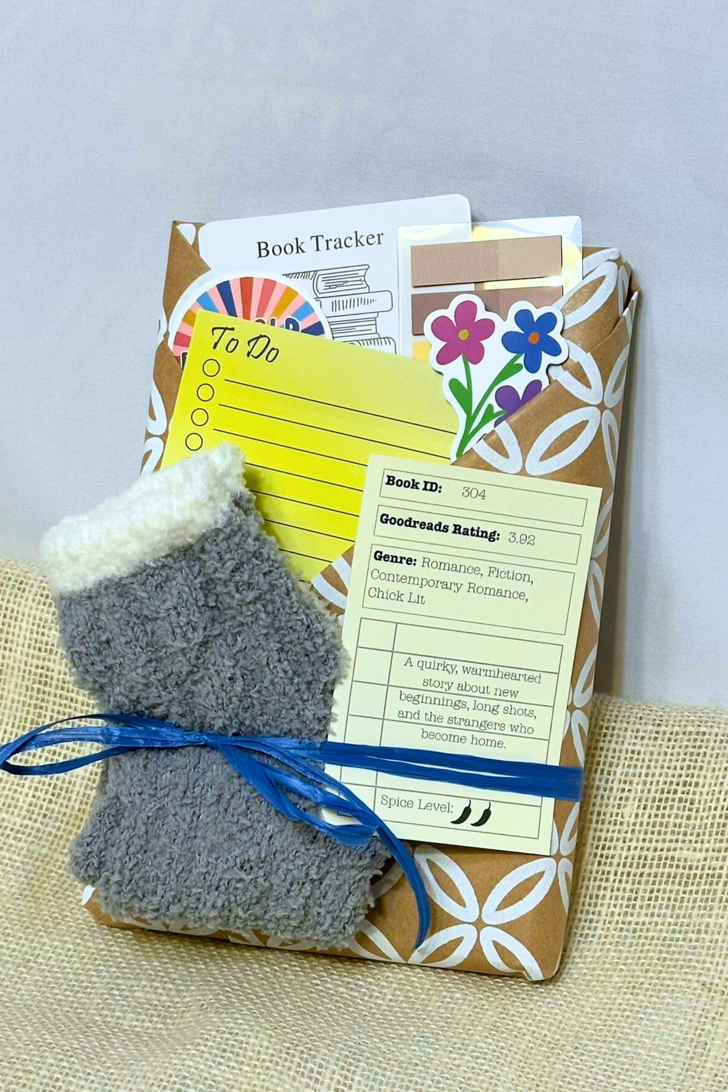 wrapped book with pockets that include a pen, sticky notes, bookmark, cozy socks and description of the book wrapped inside