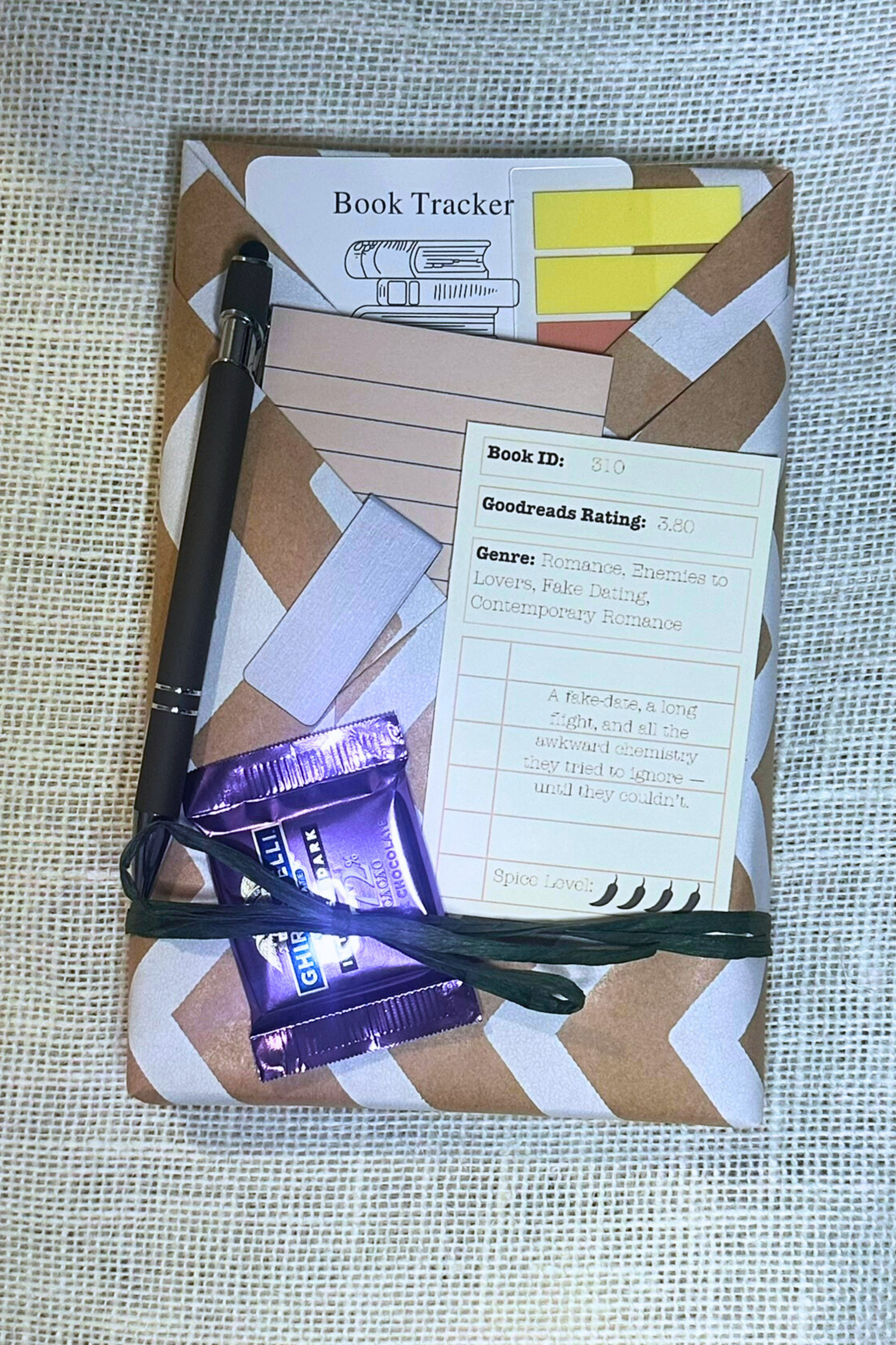 Wrapped book with pockets with book accessories inside. Including bookmark, pen, sticky notes, book tabs, and magnetic bookmark. 