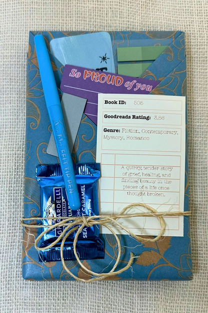 Book wrapped in paper with pockets holding pen, bookmark, sticky notes, and description of the book inside