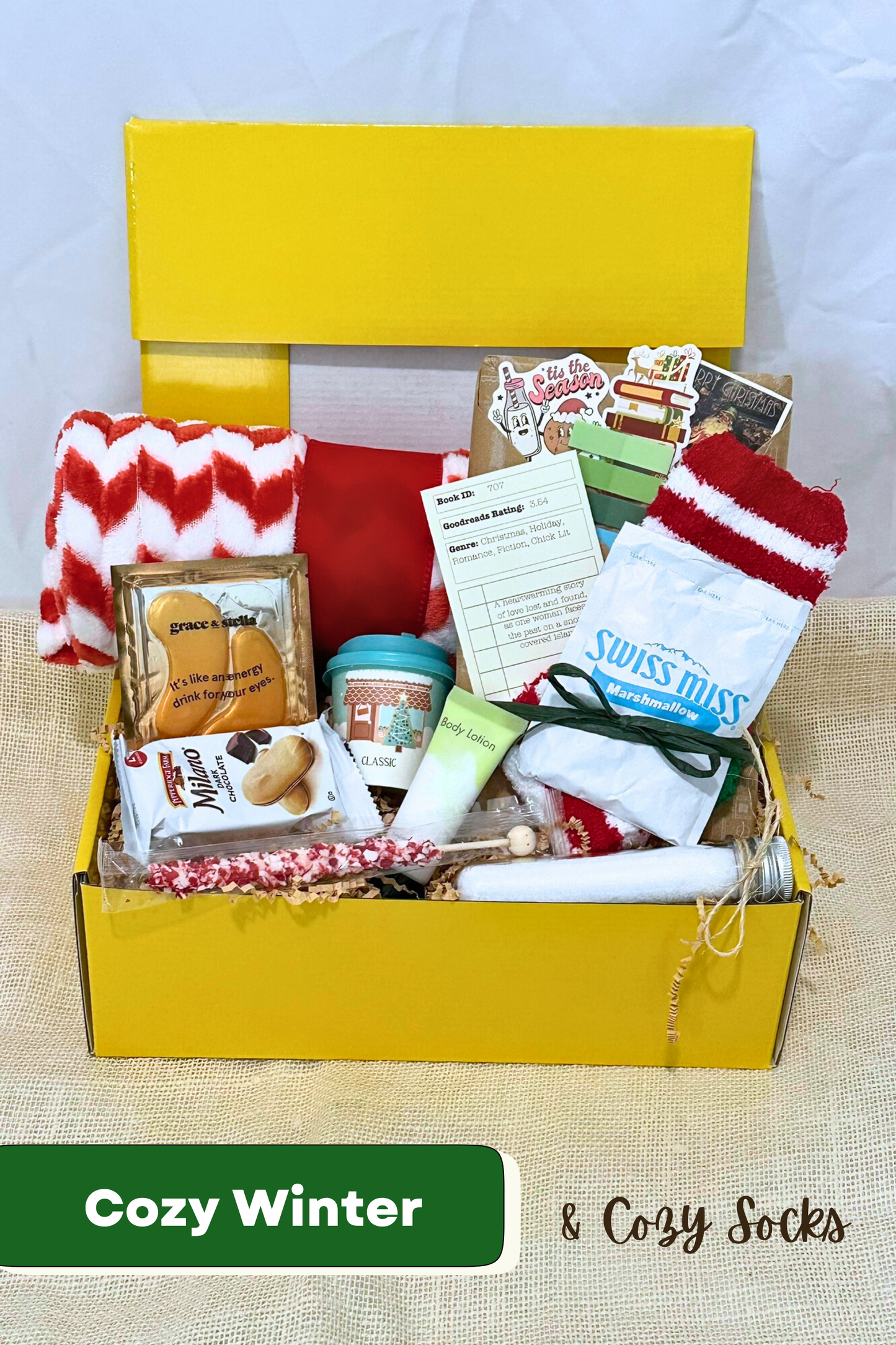 Yellow box filled with winter-themed items including socks, snacks, bath salts, fleece blanket, and blind date with a book