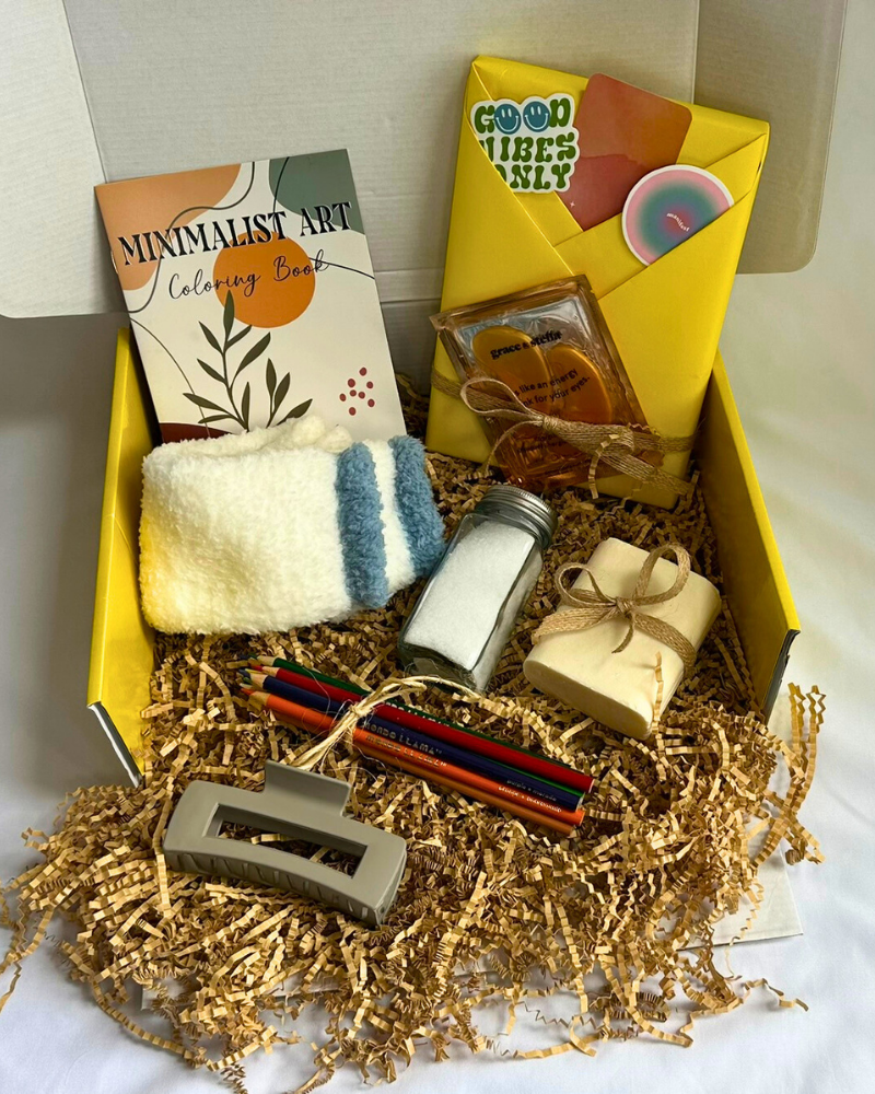 Gift Box with cozy socks, bar soap, bath salts, coloring book, colored pencils, hair clip, featuring a blind date with a book with bookish items. 